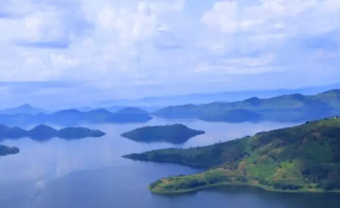 Serene view of Lake Kivu with clear blue waters and lush green surroundings.